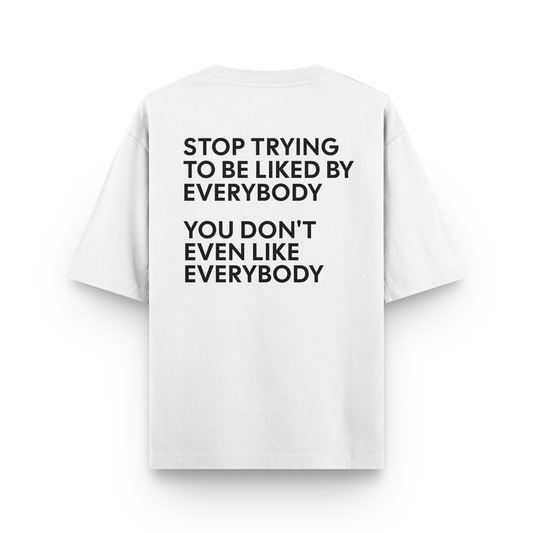 White oversized t-shirt with bold black quote saying “Stop trying to be liked by everybody / You don’t even like everybody”